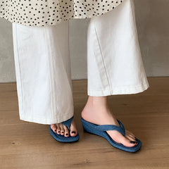 Blue denim wedge flip flops on feet