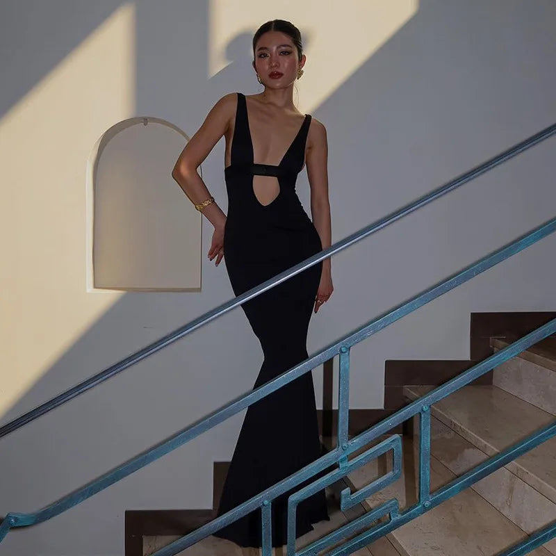 Woman in a black dress standing on a staircase with blue railings.