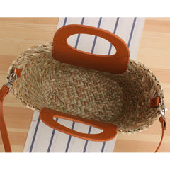 Woven handbag with orange handles on a striped fabric background