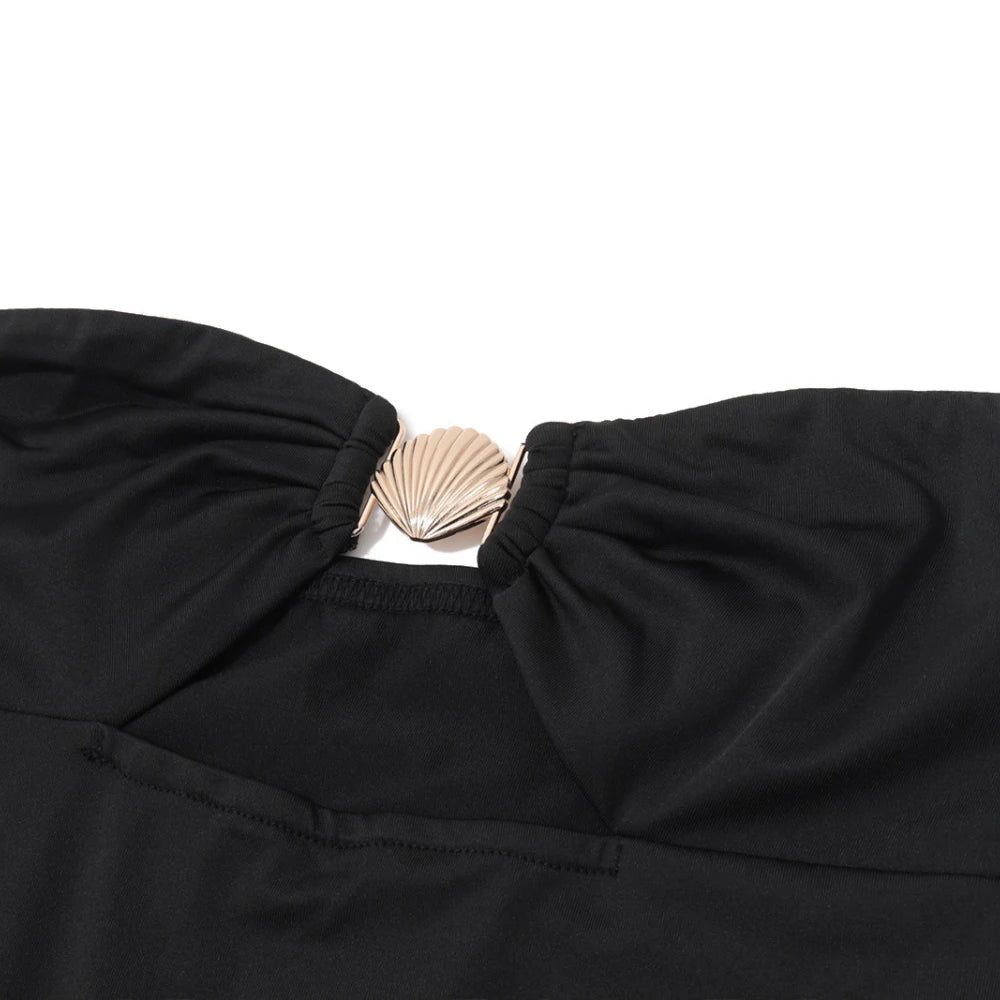 Black top with a gold brooch on a white background