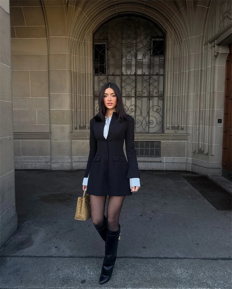 Woman in a black suit standing in front of a stone building