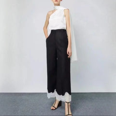 Person wearing a white sleeveless top and black pants with lace trim