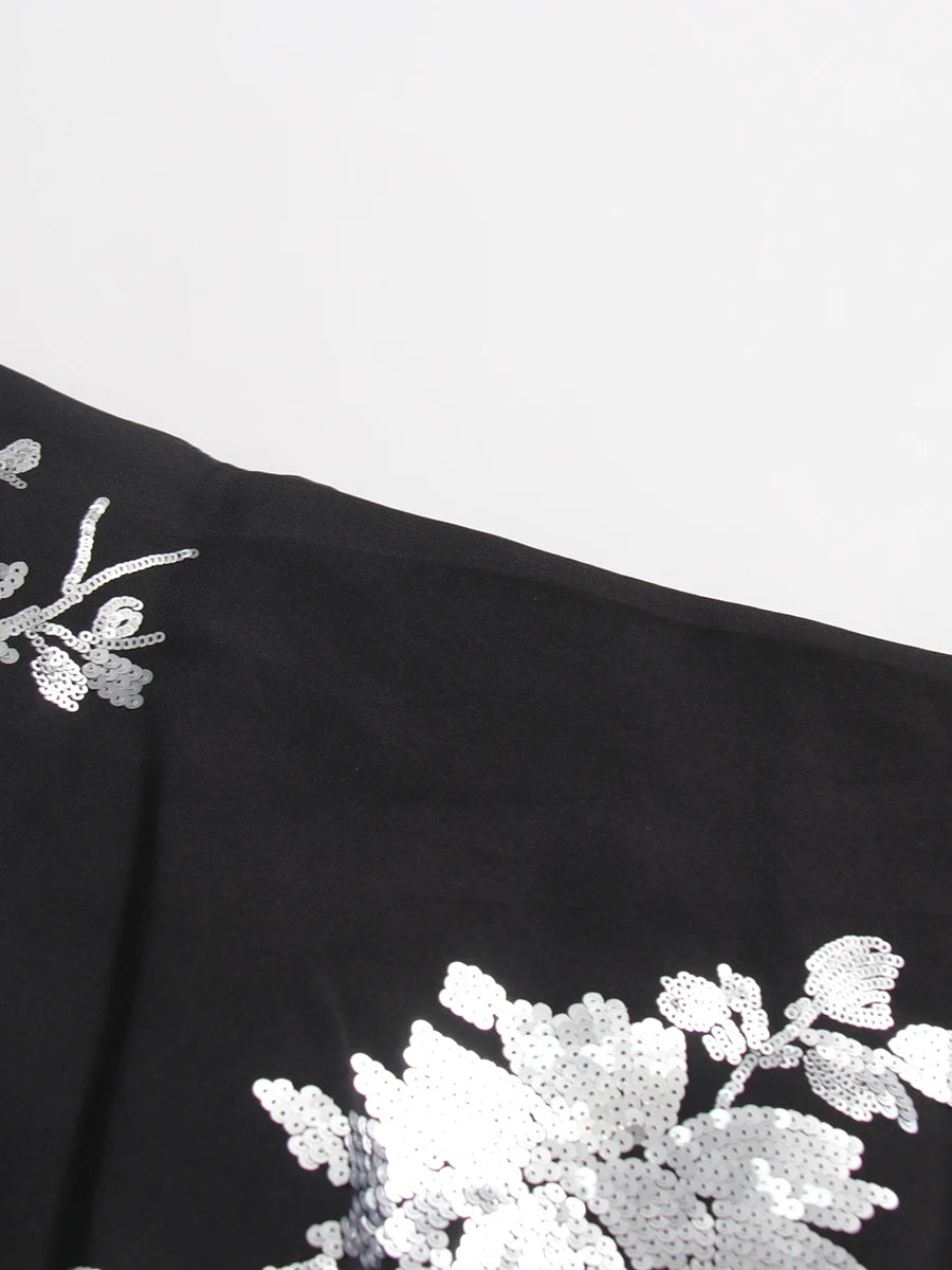 Black fabric with white floral embroidery on a light gray background