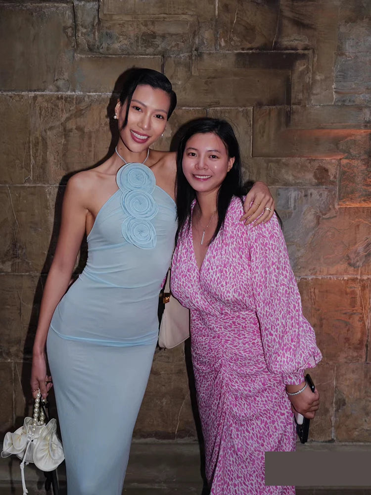Two women posing together against a stone wall.