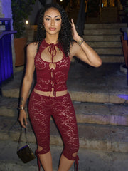 Woman in a red lace outfit posing outdoors at night.