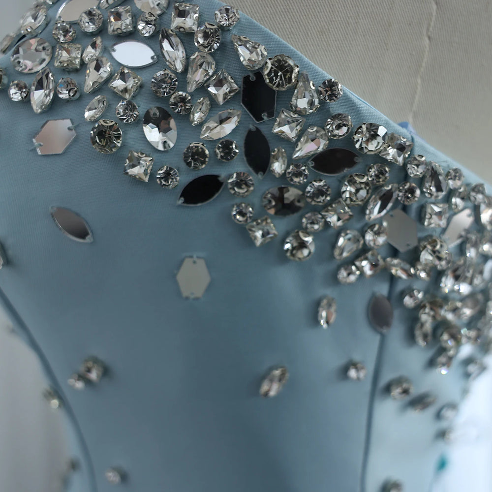 Close-up of a blue handbag with decorative crystals on a neutral background