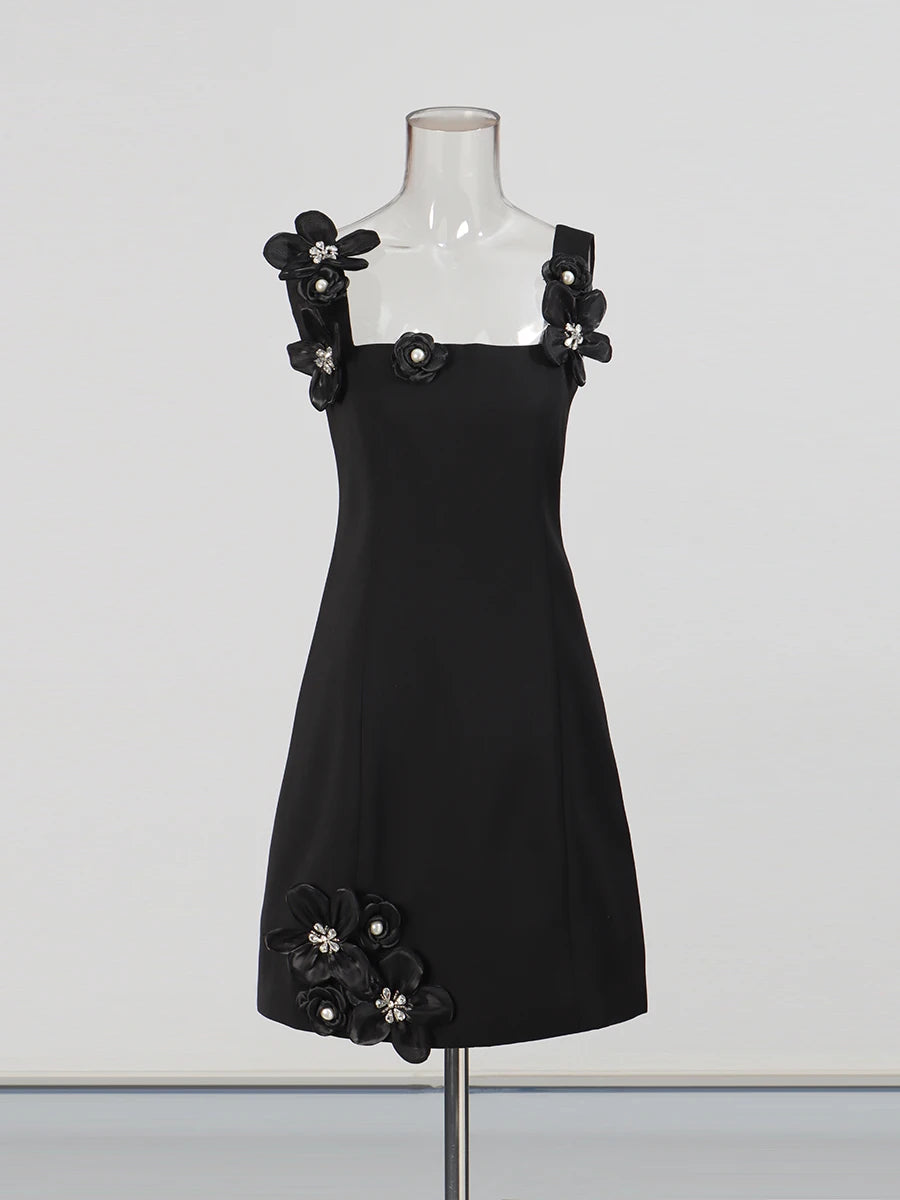 Black dress with floral embellishments on a mannequin against a white background