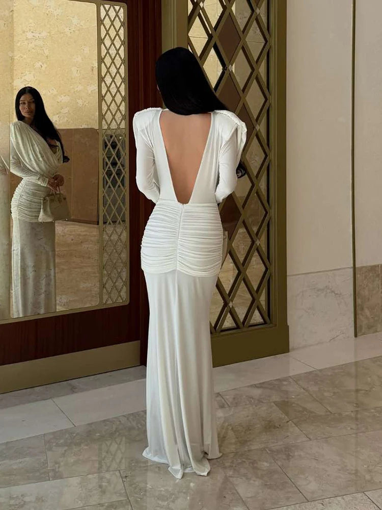 Woman in a white evening gown standing in front of a mirror.