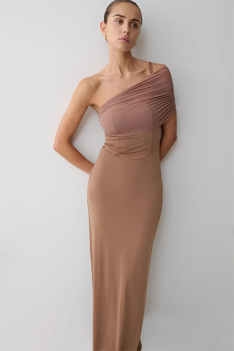 Woman wearing a one-shoulder brown dress against a white background