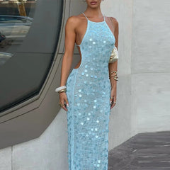 Woman wearing a sparkly blue dress standing against a modern architectural background.