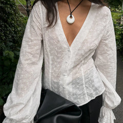 White floral blouse with a deep neckline worn by a person outdoors.