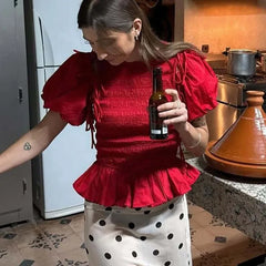 Woman wearing red ruffled smocked crop top with puff sleeves and fitted waist