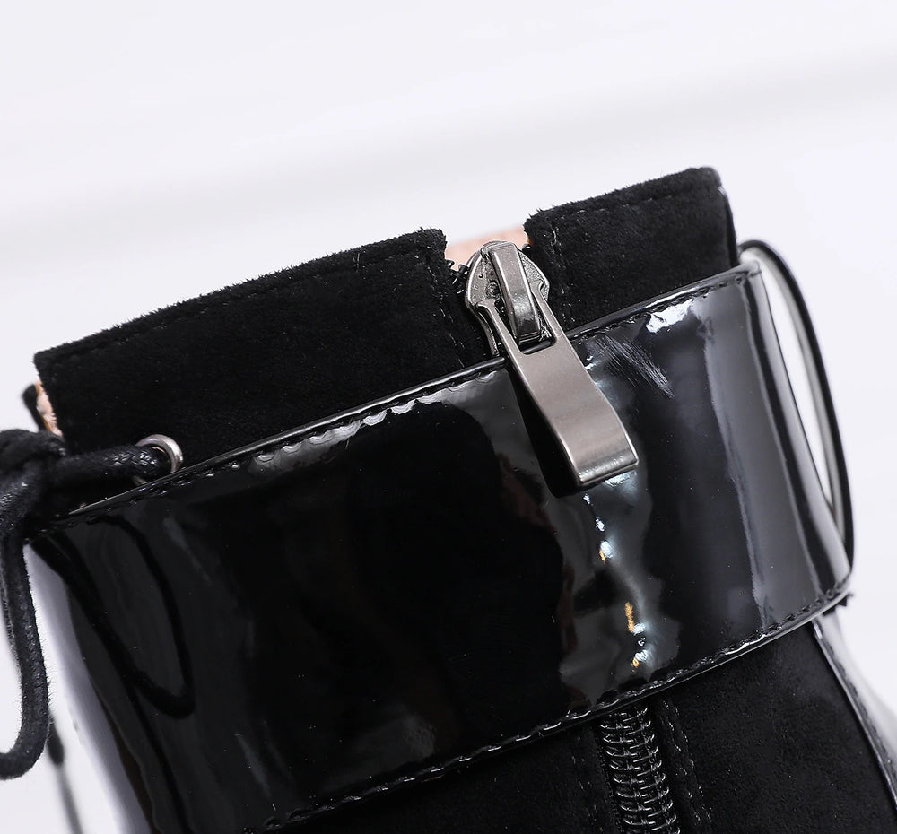 Close-up of a black patent leather handbag with a silver clasp on a white background