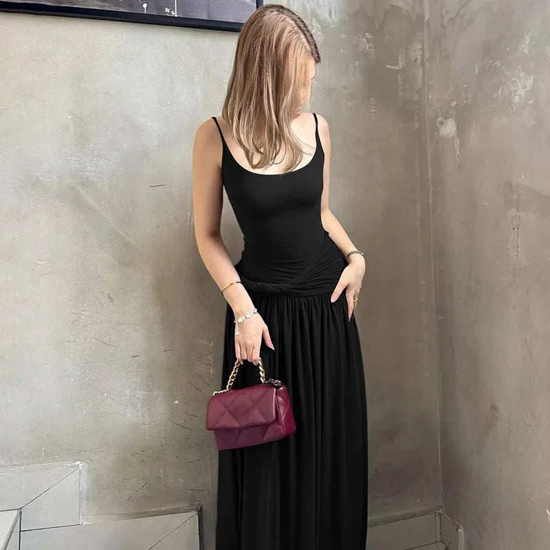 Woman in a black dress holding a purple handbag against a textured wall.