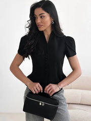 Woman holding a black handbag against a neutral background