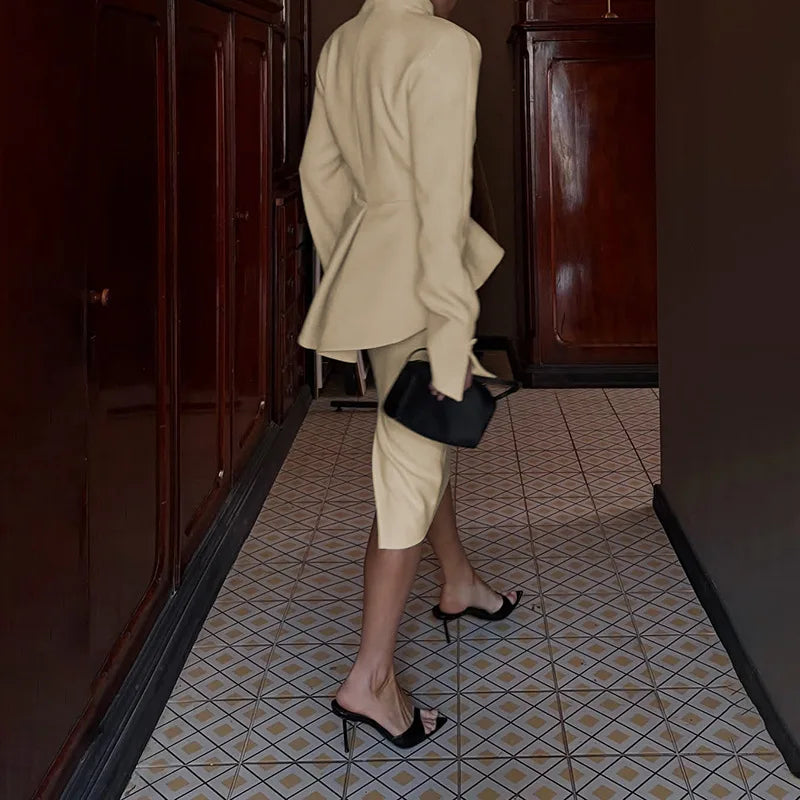 Person in a beige suit walking in a hallway with tiled floor