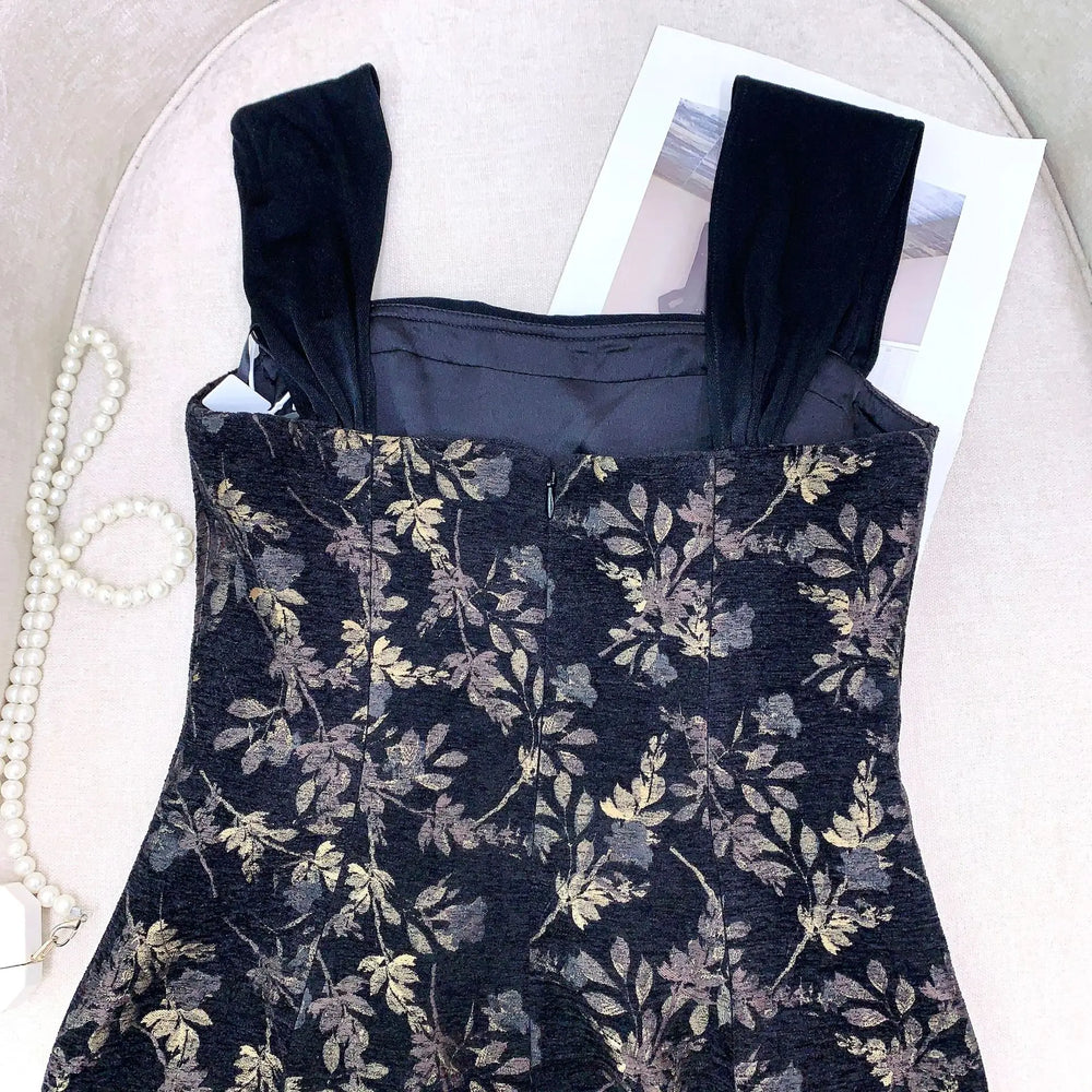 Floral patterned dress with black straps on a white surface