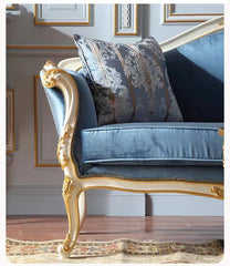 Decorative blue sofa with gold accents in a room with framed pictures on the wall.