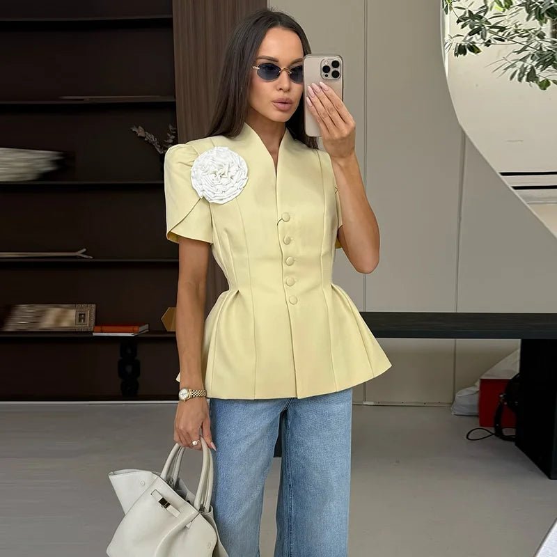 Woman taking a mirror selfie wearing a light yellow peplum top and blue jeans indoors.