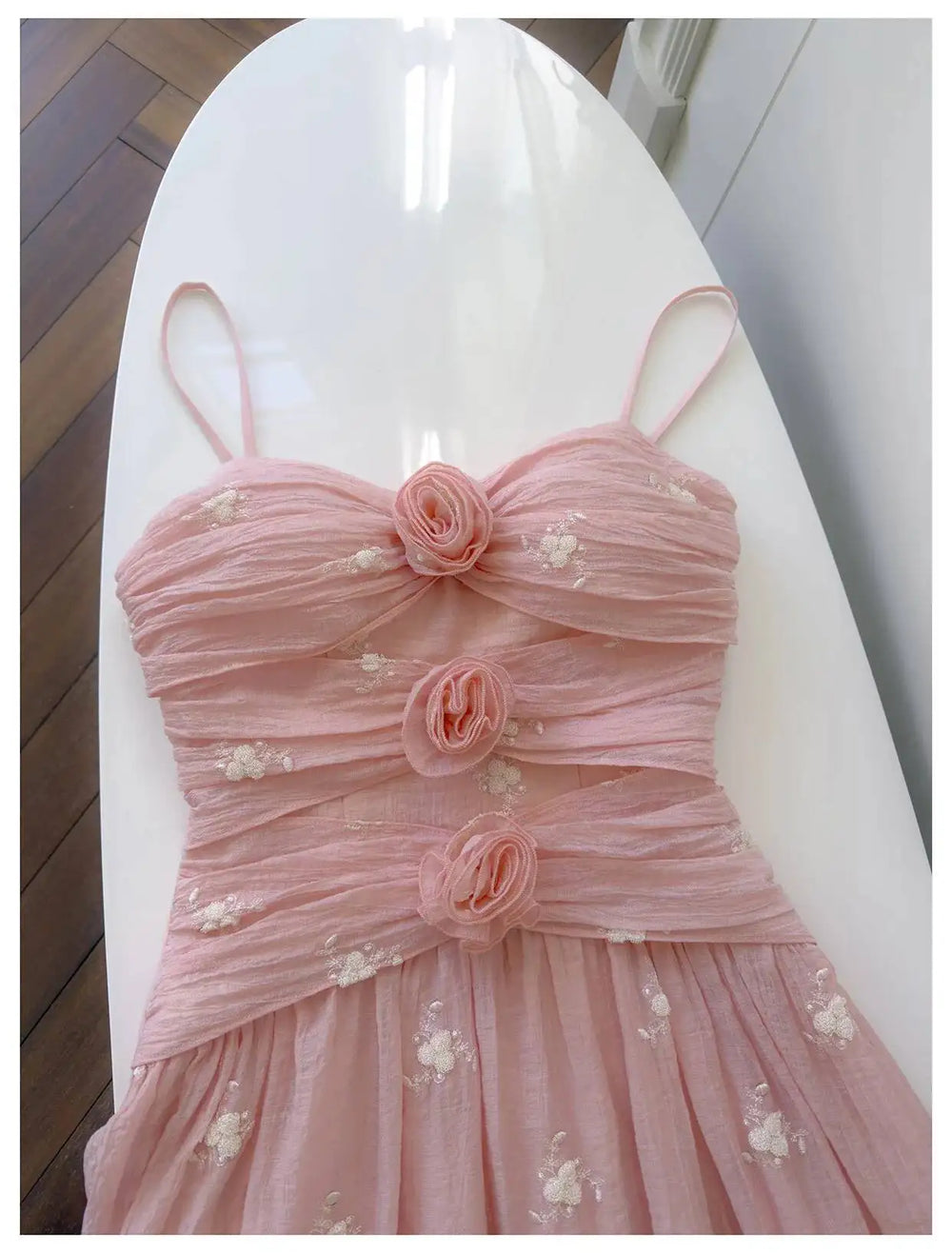 Close-up of the ruched bodice with rose embellishments on the pink midi dress