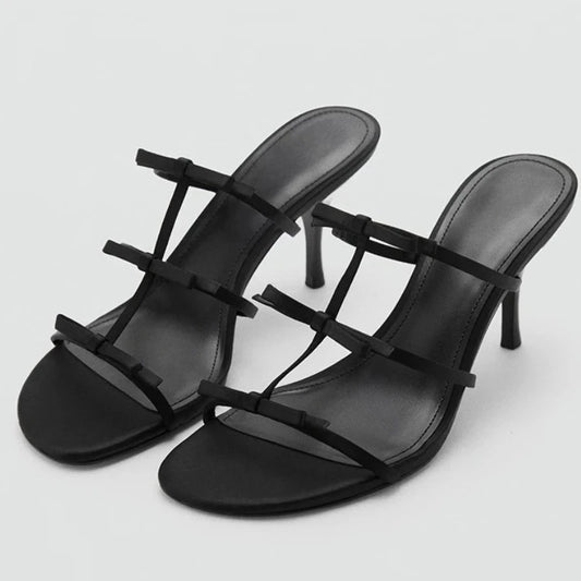 Black stiletto heels with delicate bow straps.