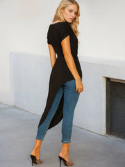 Woman wearing a black top and blue jeans against a white wall.