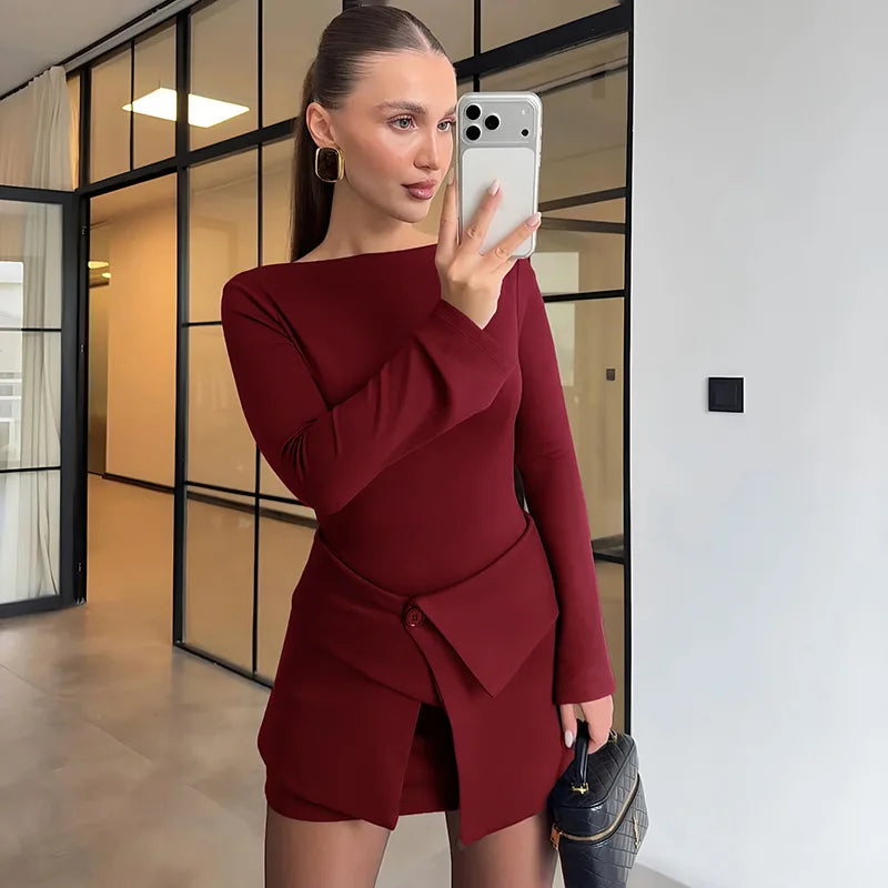 Woman in a burgundy dress taking a mirror selfie in an indoor setting.