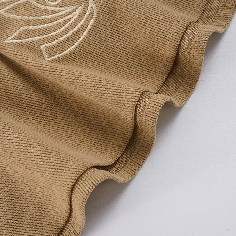 Close-up of a brown knitted garment with white embroidery on a white background