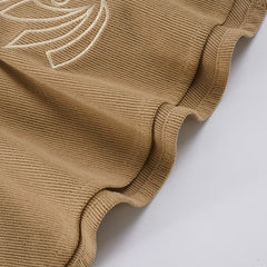 Close-up of a brown knitted garment with white embroidery on a white background