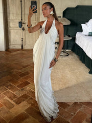 Woman in a white dress taking a selfie in a room with a bed and lamp.