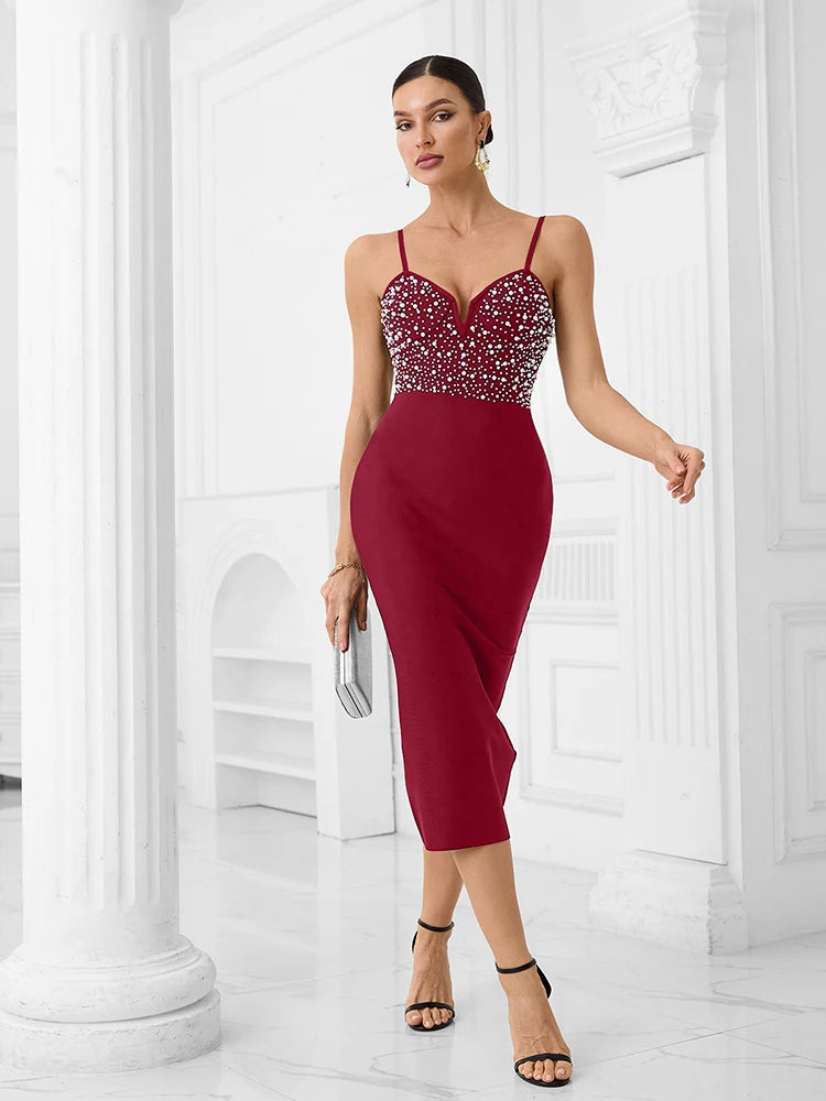 Woman wearing a burgundy dress with a beaded top in a white room.