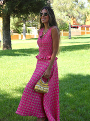 Woman in a pink dress standing on grass with trees in the background