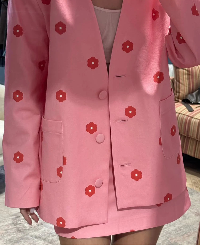 Pink blazer with red floral patterns worn by a person