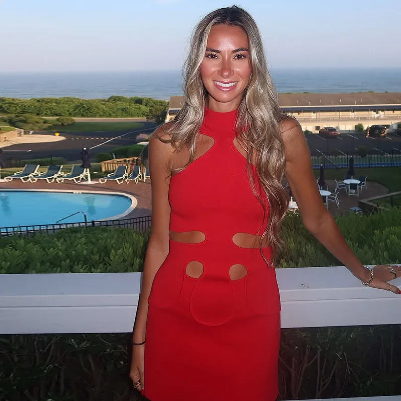 Woman in a red dress standing by a pool with a scenic background