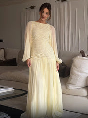 Woman in a light-colored dress standing in a living room.
