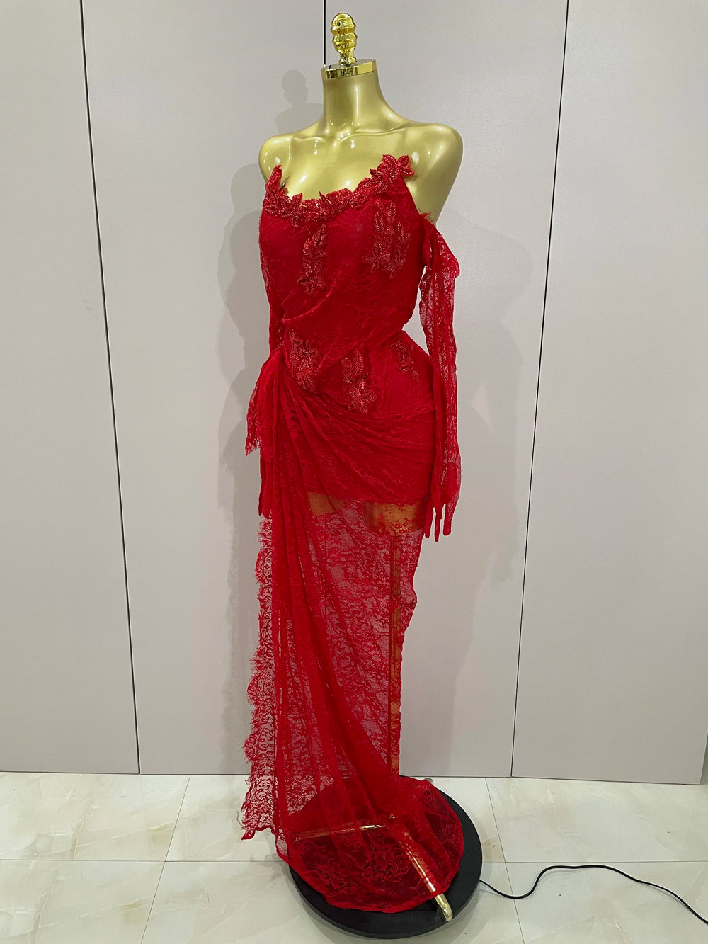 Red lace dress on a mannequin against a white wall