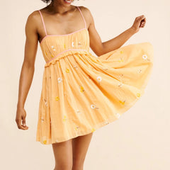 Woman wearing a yellow dress with floral patterns on a beige background