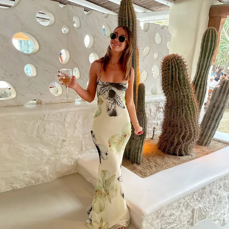Woman in a floral dress holding a drink in a modern indoor setting with cacti.