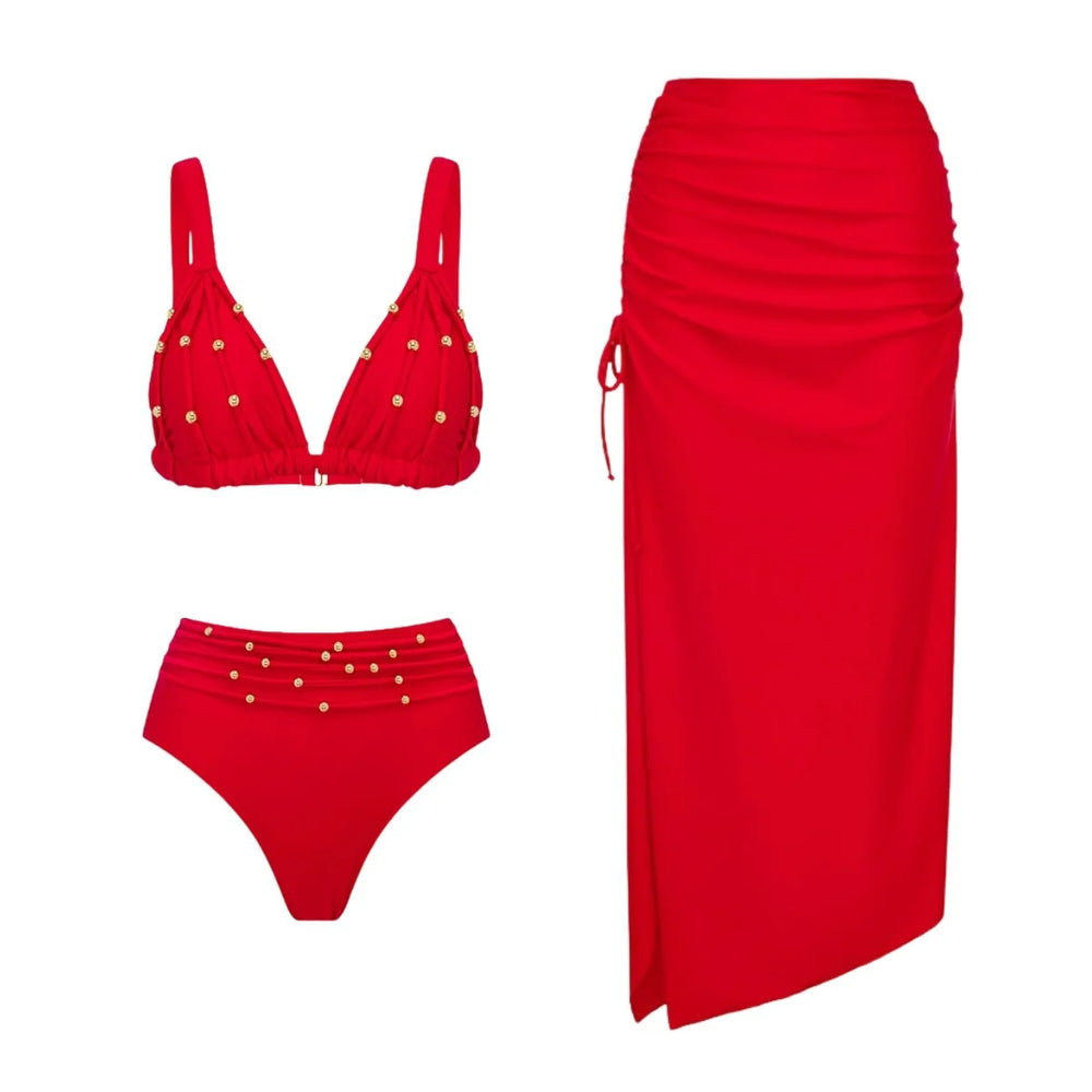 Flat lay of a red embellished bikini and a red ruched midi skirt.