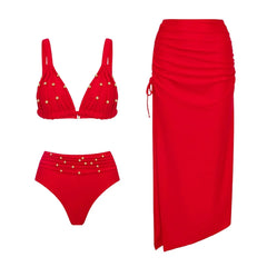 Flat lay of a red embellished bikini and a red ruched midi skirt.