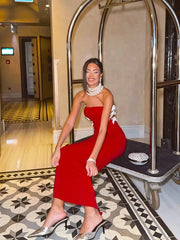 Woman in a red dress sitting on a luggage cart in an elegant hallway.