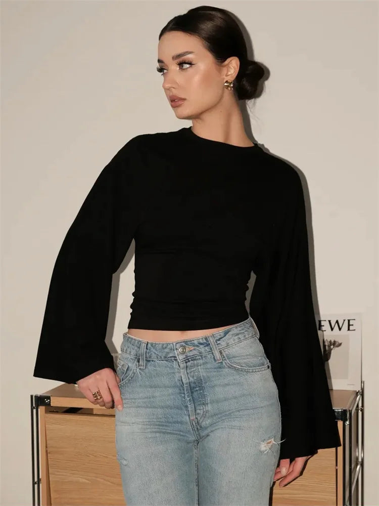 Woman wearing a black top and light blue jeans against a neutral background