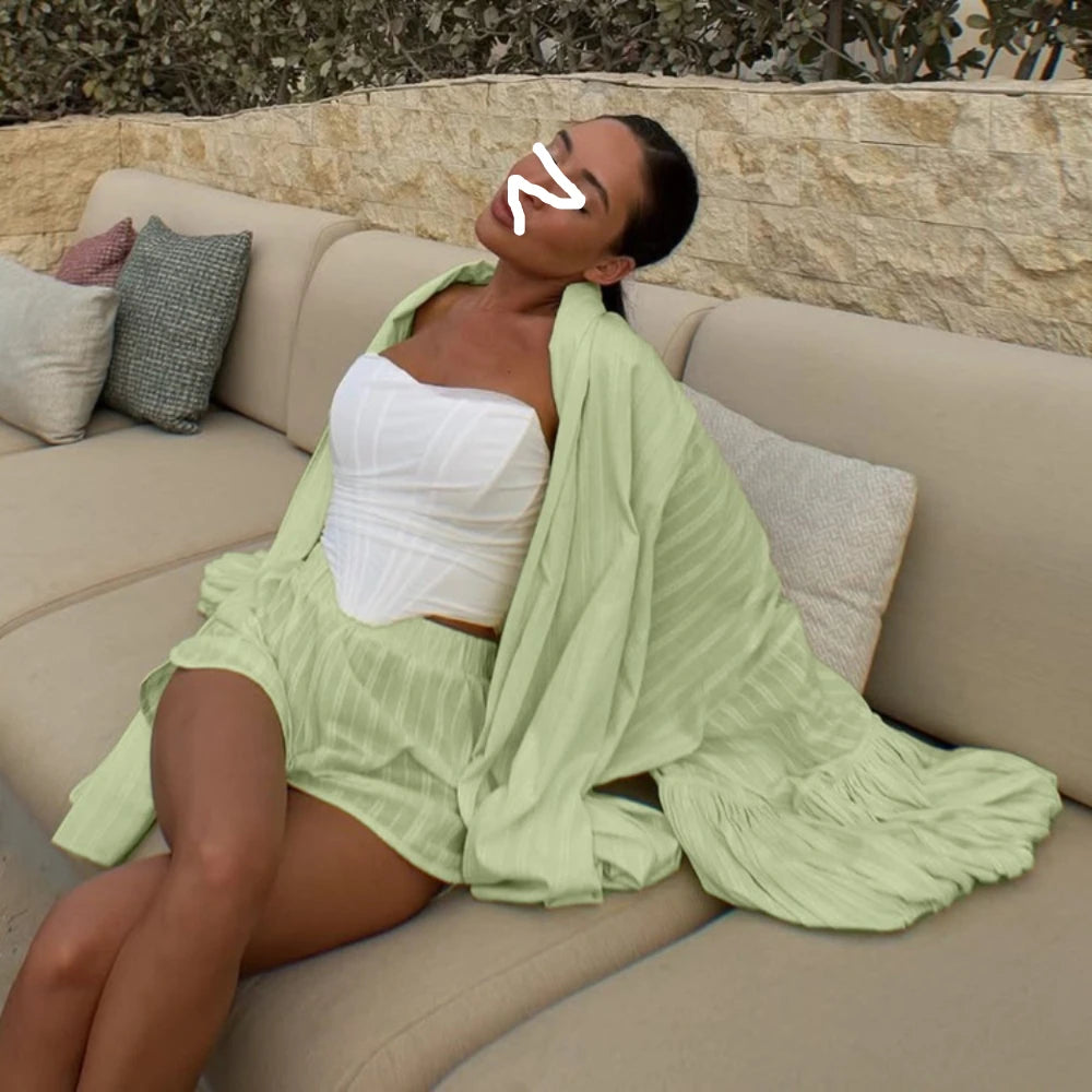 Woman in a white top and light green cover-up sitting on a beige couch outdoors.
