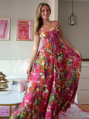 Woman wearing a colorful floral dress in a room with a white couch and framed pictures on the wall.