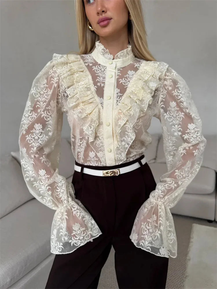 Woman wearing a white lace blouse with long sleeves in an indoor setting.