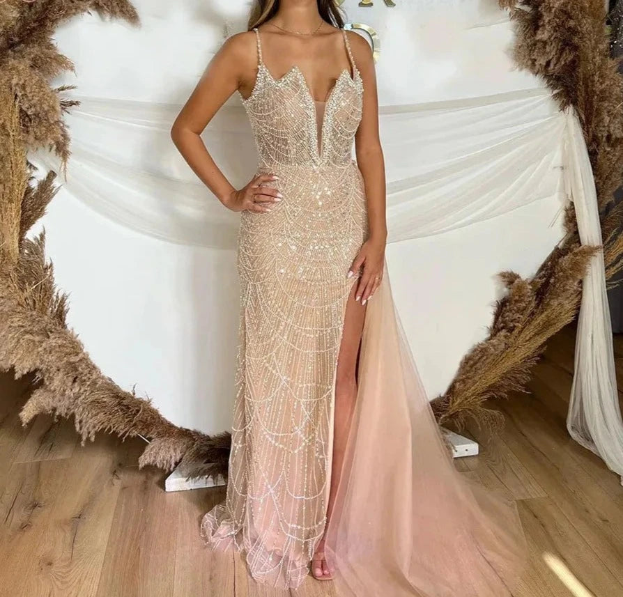 A model wearing a stunning pearl mermaid gown with spaghetti straps and a side slit, perfect for prom or formal events. 1