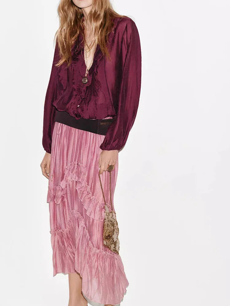 Full view of a person in a pink ruffled maxi skirt and dark top.
