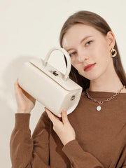 Structured white leather top handle bag held by a woman