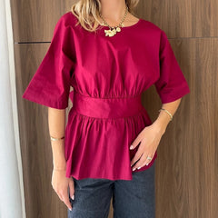 Person wearing a bright pink blouse with a wooden wall background