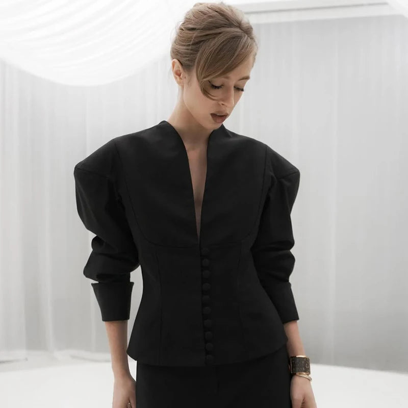 Woman wearing a black outfit with puffed sleeves against a white background